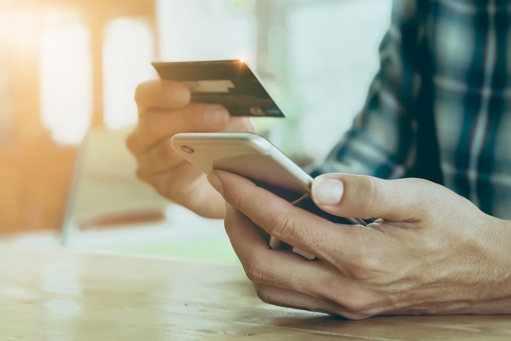 man holding phone and paying online with credit card