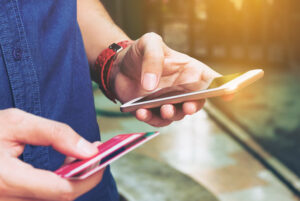 man using phone and holding credit card