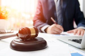 gavel on a desk with lawyer writing in the background